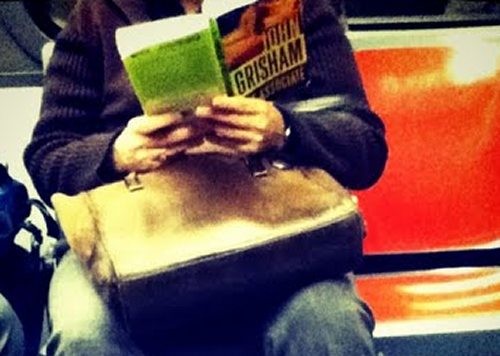 Someone-reading-the-Associate-by-John-Grisham-on-a