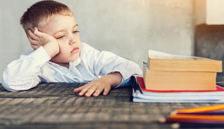 aluno-cansado-pequeno-que-olha-seus-livros-1184316