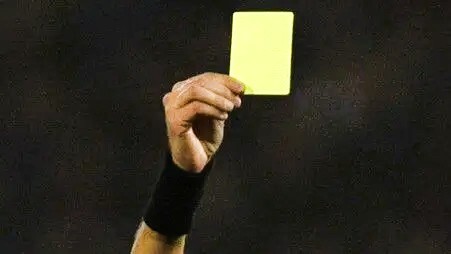 A_referee_s_hand_showing_a_yellow_card_in_football