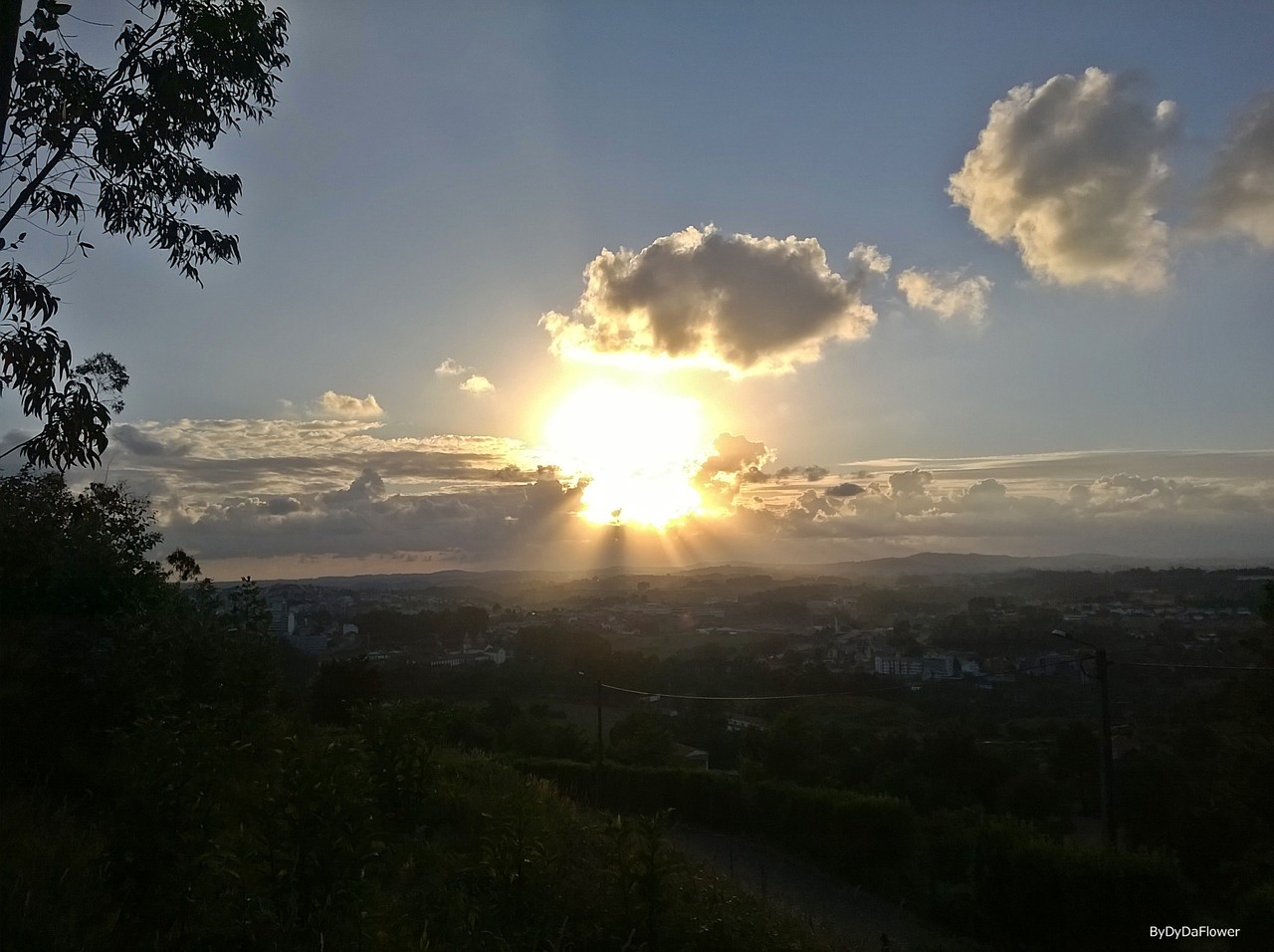 A cidade por o sol por entre nuvens.jpg