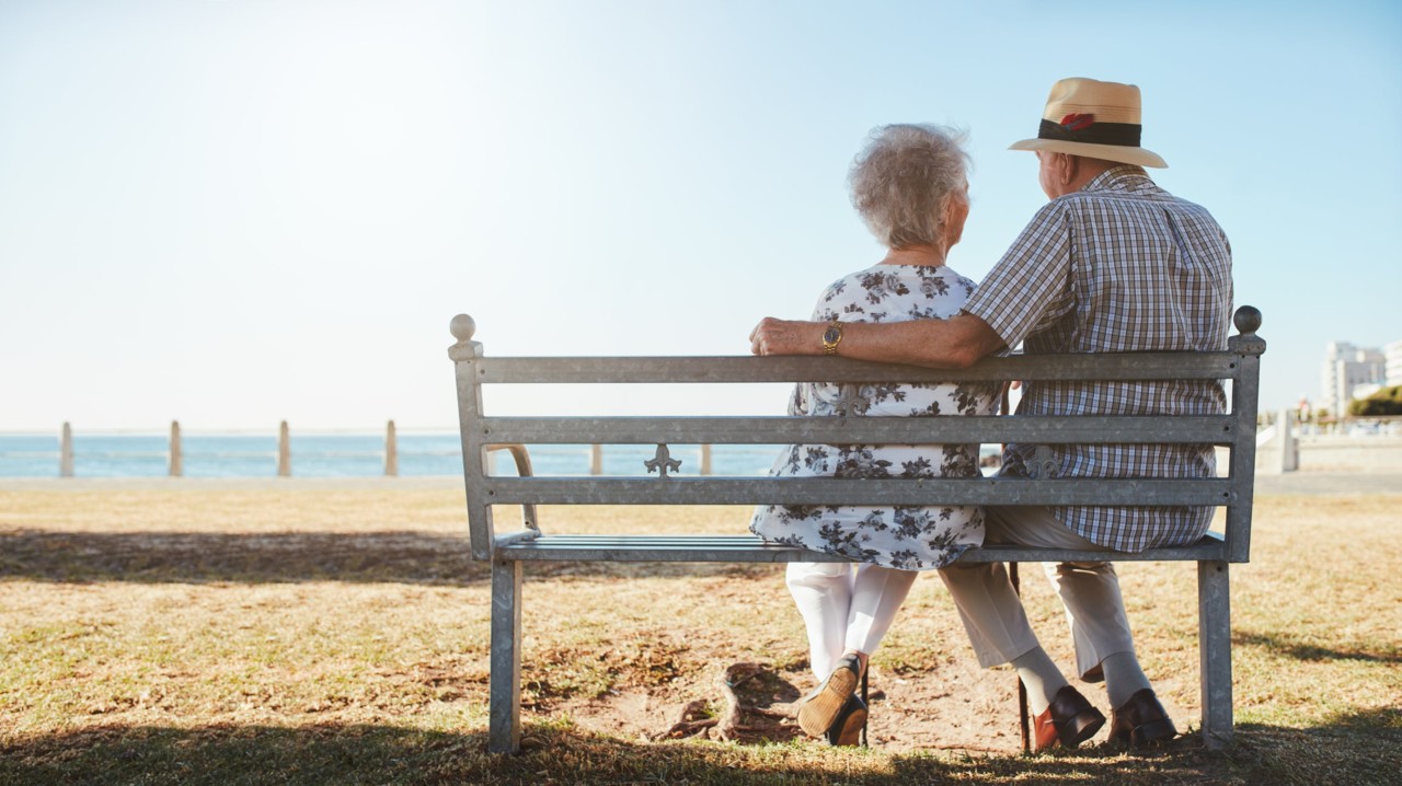 elderly-senior-couple-sitting-on-a-bench-on-the-be elderly-senior-couple-sitting-on-a-bench-on-the-be